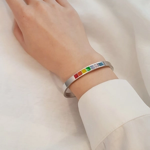 Detail view of silver C-shaped titanium steel bracelet with rainbow enamel square inlay