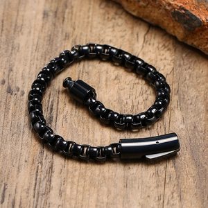 Detail of a black stainless steel box chain bracelet with a secure push-plug clasp on wood