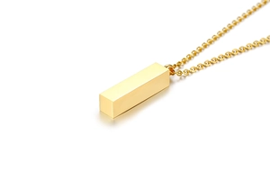 Detailed close-up of a minimalist gold cuboid pendant and sleek stainless steel chain