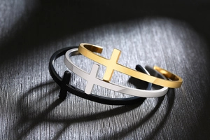Detailed close-up of C-shaped stainless steel cross bracelets in gold, silver, and black