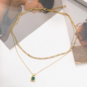 Detail of gold double layer necklace with green rectangular pendant and figaro chain