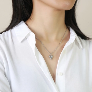Collier élégant avec pendentif cœur poli sur chaîne maille porté sur chemise blanche