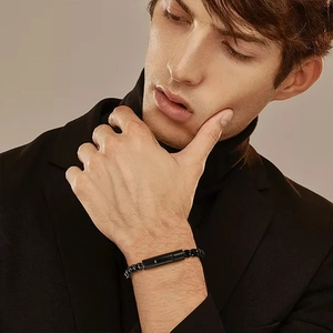 Detail of men black beaded bracelet with matte metal cylinder on model wrist