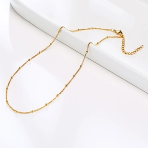 Detail of thin gold beaded necklace with lobster clasp and adjustable extension chain