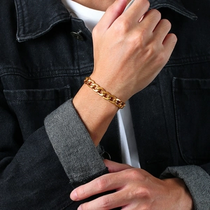 Nahaufnahme eines polierten goldenen Panzerarmbands am Handgelenk eines Mannes über einer Jacke