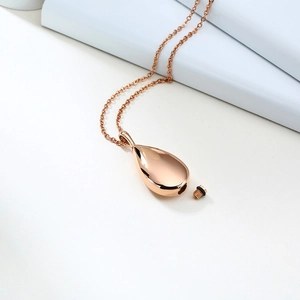 Macro detail of rose gold teardrop urn pendant featuring secure screw closure and seal