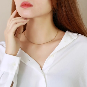 Delicate 2mm gold-plated stainless steel bead chain necklace worn on a female neck
