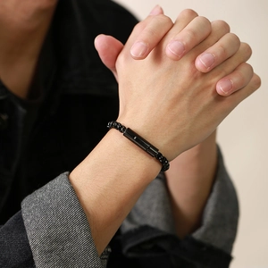 Close-up of men's black beaded bracelet with a polished metal cylinder on wrist