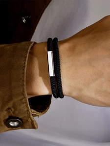 Detail of double-layer black woven bracelet with silver metal slide on man's wrist