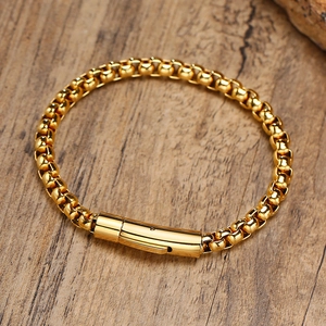 Detail of 18K gold-plated box chain bracelet with cylindrical clasp on a wooden surface