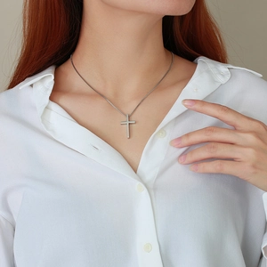 Minimalist silver cross pendant necklace on fine box chain worn over a white shirt