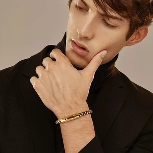 Detail of men's gold-plated stainless steel box chain bracelet worn with a black suit