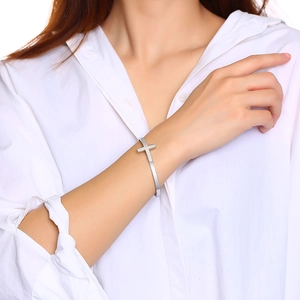 Minimalist silver stainless steel cross cuff bracelet shown on a model wrist