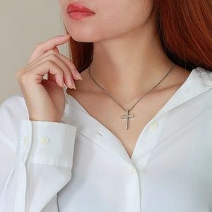 Detailed close-up of a silver stainless steel cross pendant necklace on a box chain