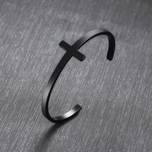 Macro shot of matte black stainless steel cuff bracelet with cross detail on brushed metal