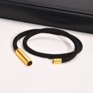 Detailed view of black woven rope bracelet with polished gold magnetic closure