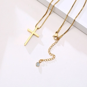 Gold stainless steel cross pendant necklace with box chain on a minimalist white display
