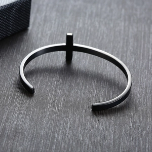 Detail of black brushed stainless steel open cuff bracelet with minimalist cross design