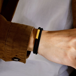 Detailed shot of double-layered black woven bracelet with polished gold magnetic clasp