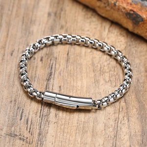 Detail of silver box chain bracelet with modern cylindrical clasp on wooden background