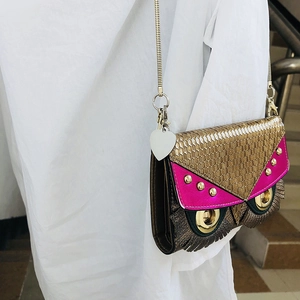 Detailed view of an owl-shaped shoulder bag featuring large gold eyes and a heart charm