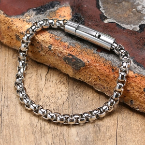 Detail of 6mm polished stainless steel box chain bracelet on a natural rock surface