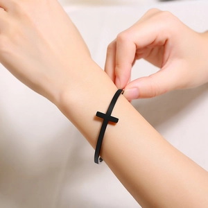 Close-up of minimalist black matte cross cuff bracelet worn on person wrist