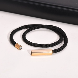 Detail view of black braided Milan rope bracelet with golden magnetic square clasp