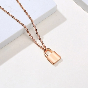 Detailed view of a rose gold padlock pendant on a sleek chain over stone steps