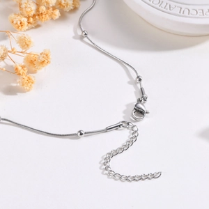 Macro view of silver snake chain necklace with round beads and lobster clasp closure