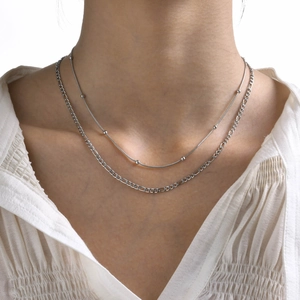 Close-up of double layered stainless steel necklace with bead snake and Figaro chain
