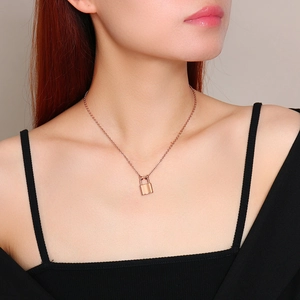 Detail of rose gold padlock pendant necklace on model with fine link chain