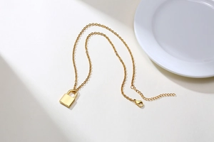 Detail shot of golden lock pendant necklace with adjustable chain and lobster clasp