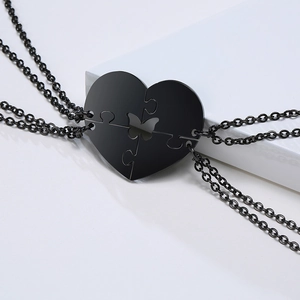 Dettaglio di quattro collane puzzle a cuore in acciaio inox nero con intaglio farfalla
