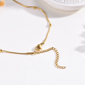 Close-up of golden snake chain necklace with round beads, lobster clasp and extender chain