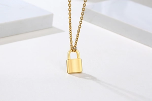 Detailed view of a polished gold-plated lock pendant hanging on a delicate necklace chain