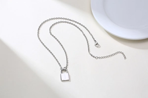 Macro view of polished stainless steel padlock pendant necklace with lobster clasp closure