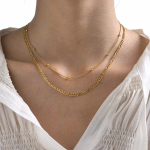 Close-up of double-layer gold stainless steel necklace with bead snake and Figaro chain