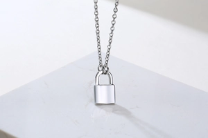 Macro shot of silver padlock pendant on o-chain over white marble background