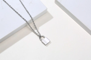 Close-up of a silver stainless steel padlock pendant necklace on marble background