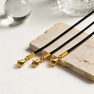 Three-piece black wax cord necklaces with gold metal lobster clasps on a stone plate
