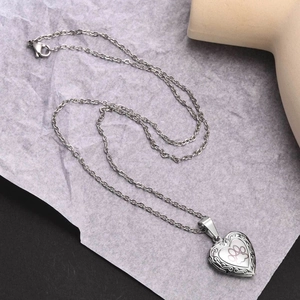 Dettaglio della collana con medaglione a cuore in acciaio inox con zampa rosa e incisioni
