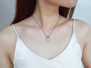 Detail of a silver stainless steel padlock pendant necklace worn by a female model