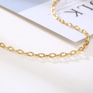 Close-up of golden oval link chain with faceted diamond-cut texture and polished finish