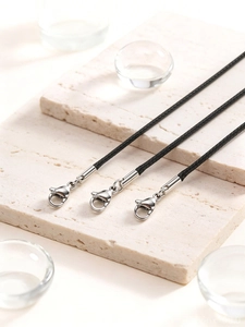 Close-up of three black braided wax cord necklaces with silver lobster clasps on stone