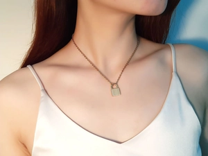 Detailed view of a gold lock pendant necklace worn on neck with professional lighting