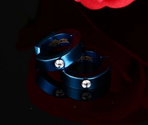 Détail des boucles d'oreilles en acier bleu avec zircon sur une surface noire miroir
