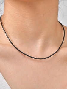 Close-up of minimalist black braided wax cord choker necklace showing fine woven texture