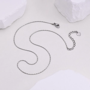 Détail d'un collier argenté avec fermoir mousqueton et pendentif en forme de cœur