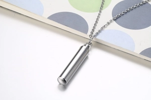 Close-up of a silver cylindrical perfume bottle pendant with mirror-polished finish